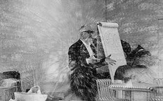 Ein Mann erklärt etwas vor einem Flipchart in einem Raum.