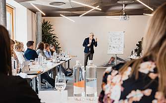 Ein Referent spricht vor einer Gruppe in einem modernen Seminarraum.